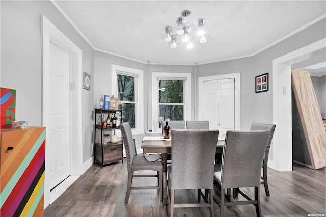 dining space featuring dark hardwood / wood-style flooring, ornamental molding, a textured ceiling, and a chandelier