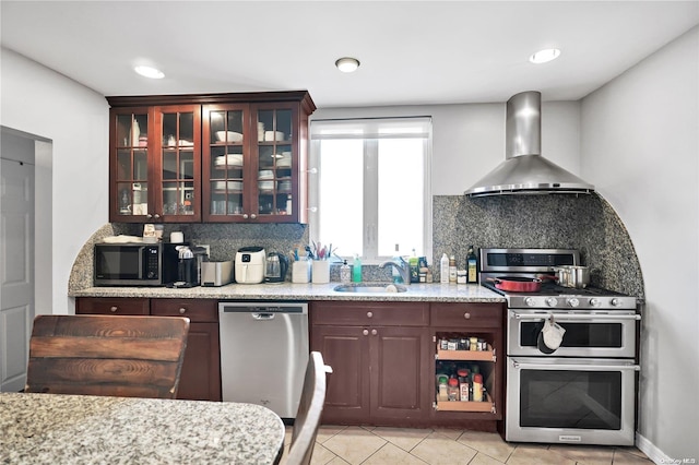 kitchen with decorative backsplash, sink, stainless steel appliances, and wall chimney range hood