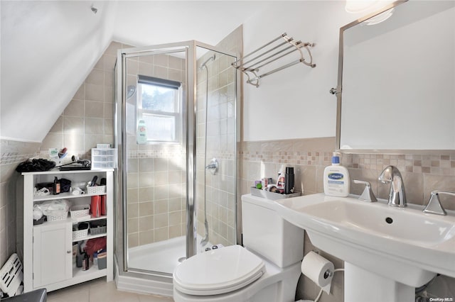 bathroom featuring sink, tile patterned floors, toilet, a shower with shower door, and tile walls