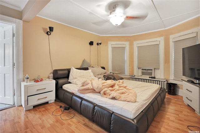 bedroom featuring ceiling fan, crown molding, light wood-type flooring, and radiator heating unit