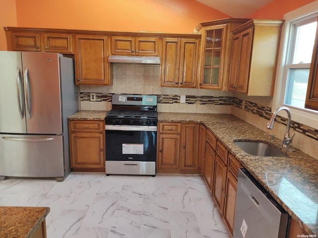 kitchen featuring decorative backsplash, stone counters, sink, and appliances with stainless steel finishes