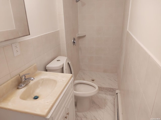 bathroom featuring vanity, toilet, baseboard heating, tiled shower, and tile walls