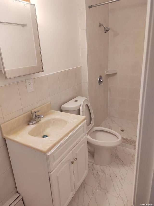 bathroom with backsplash, vanity, tiled shower, tile walls, and toilet