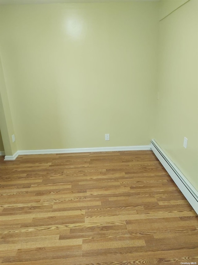 spare room featuring a baseboard heating unit and light hardwood / wood-style flooring