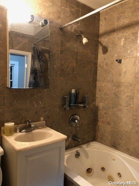 bathroom featuring tile walls, vanity, and shower / tub combo