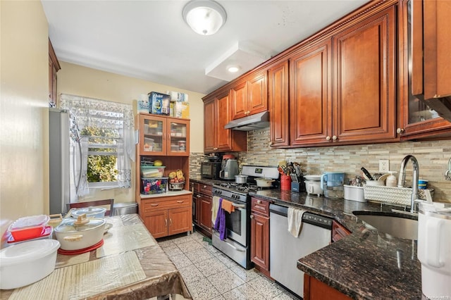 kitchen with tasteful backsplash, dark stone countertops, sink, and appliances with stainless steel finishes