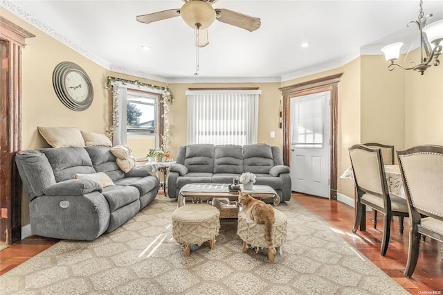 living room featuring hardwood / wood-style floors, ceiling fan with notable chandelier, and crown molding