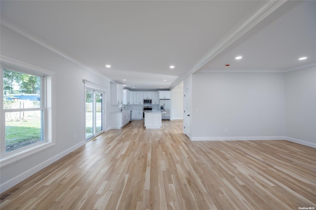 unfurnished living room with crown molding, sink, and light hardwood / wood-style floors