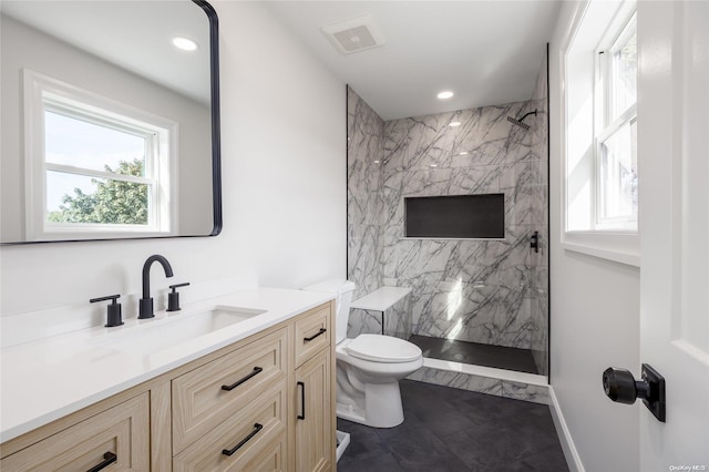 bathroom featuring tile patterned flooring, vanity, toilet, and tiled shower