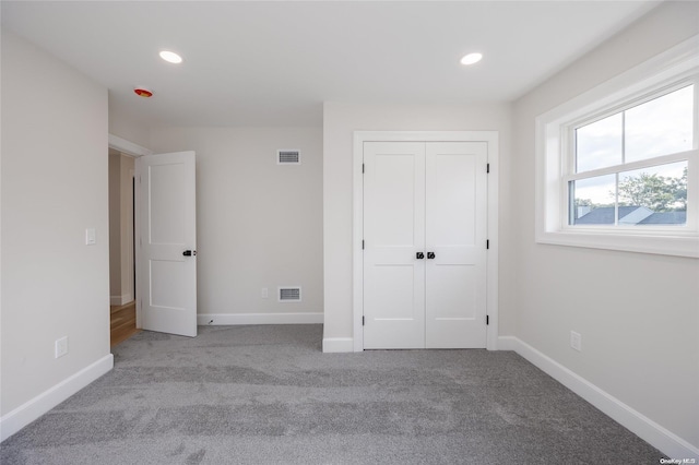 unfurnished bedroom with a closet and light colored carpet