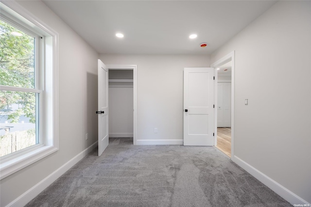 unfurnished bedroom featuring light colored carpet and multiple windows