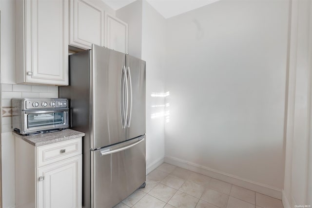 kitchen featuring white cabinets, stainless steel fridge, and light tile patterned floors