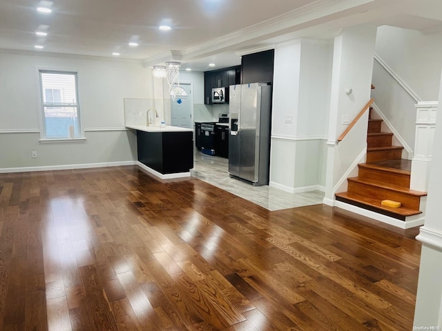 kitchen featuring sink, backsplash, kitchen peninsula, appliances with stainless steel finishes, and ornamental molding