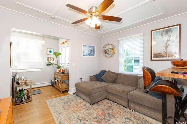 living room featuring baseboard heating, a wealth of natural light, ceiling fan, and light wood-type flooring