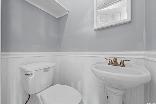 bathroom with toilet, sink, and wooden walls