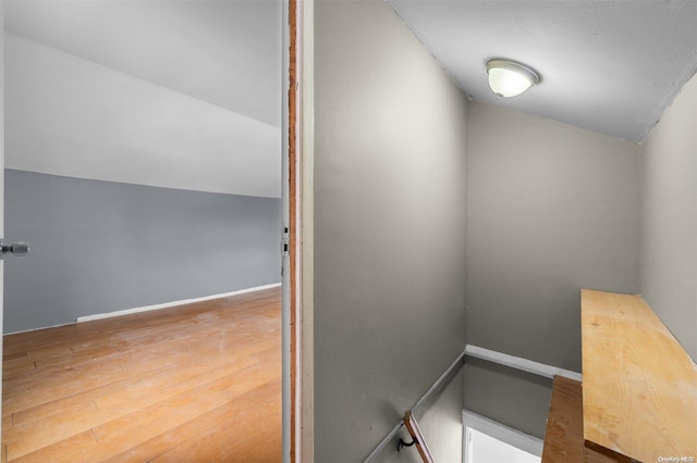 staircase with hardwood / wood-style flooring and lofted ceiling