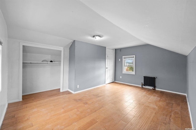 bonus room with wood-type flooring, radiator heating unit, and vaulted ceiling