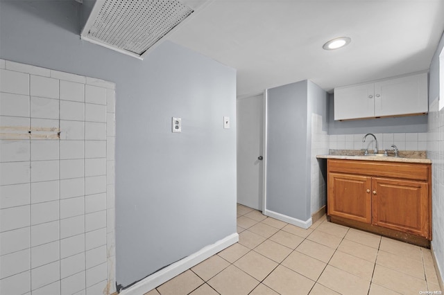 kitchen featuring light tile patterned flooring, sink, and tile walls