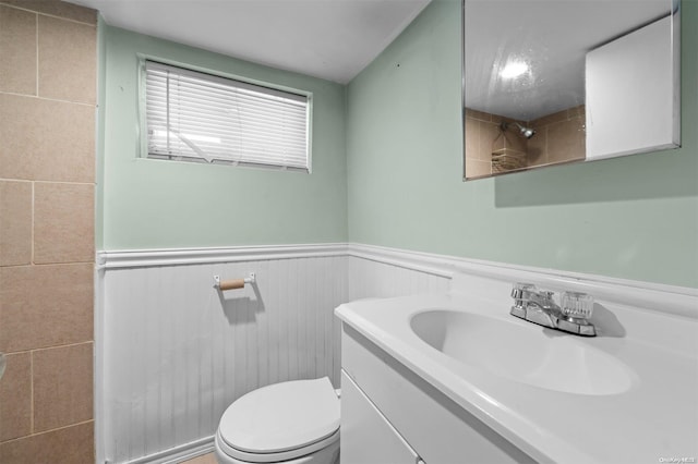 bathroom featuring vanity, tile walls, and toilet