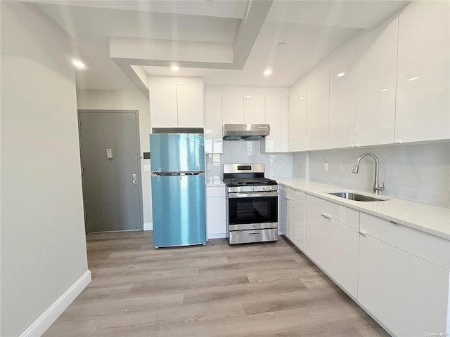 kitchen with stainless steel appliances, white cabinetry, light hardwood / wood-style floors, and sink