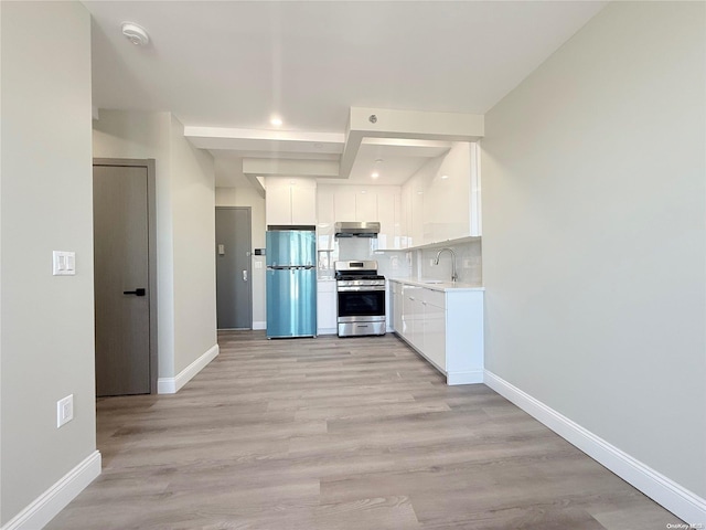 kitchen featuring sink, light hardwood / wood-style flooring, decorative backsplash, appliances with stainless steel finishes, and white cabinetry