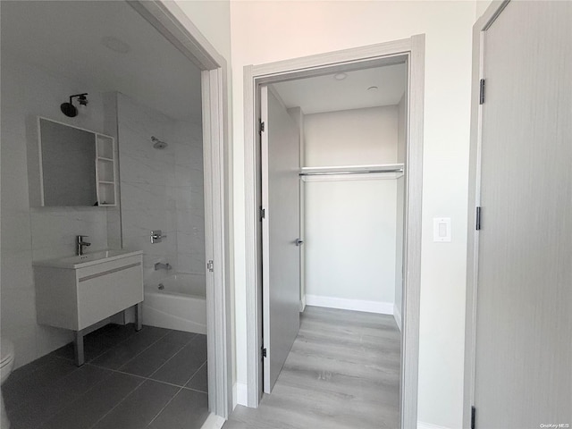 full bathroom featuring hardwood / wood-style floors, vanity, tiled shower / bath combo, and toilet