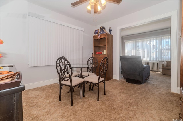 dining space with light colored carpet, radiator, and ceiling fan