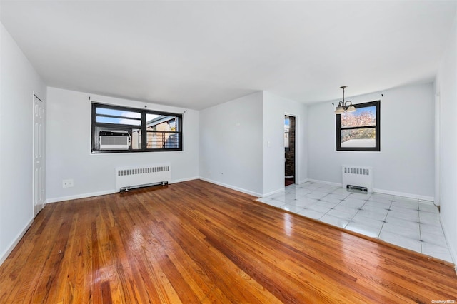 unfurnished living room featuring a wealth of natural light, light hardwood / wood-style floors, and radiator