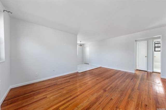 empty room featuring a notable chandelier and wood-type flooring