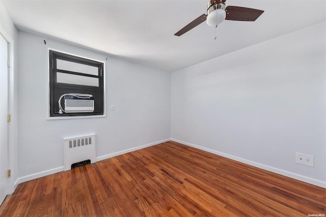 spare room with ceiling fan, radiator heating unit, cooling unit, and hardwood / wood-style flooring