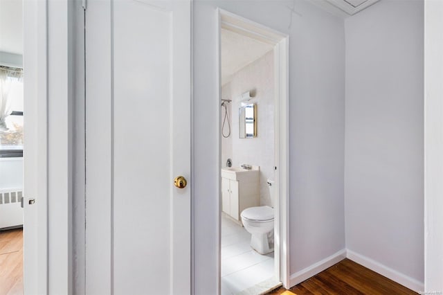 bathroom featuring hardwood / wood-style flooring, vanity, toilet, and radiator heating unit