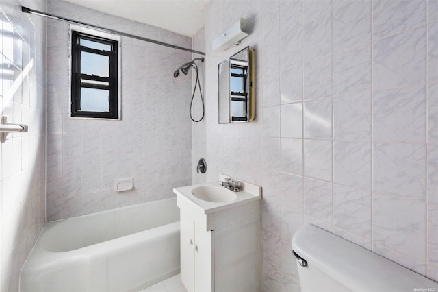 full bathroom featuring tiled shower / bath, vanity, tile walls, and toilet