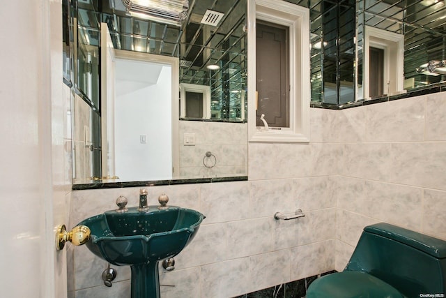 bathroom with toilet and tile walls