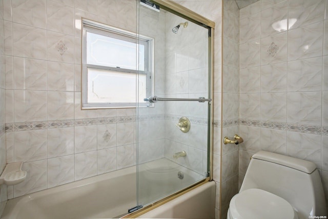 bathroom with combined bath / shower with glass door, toilet, and tile walls