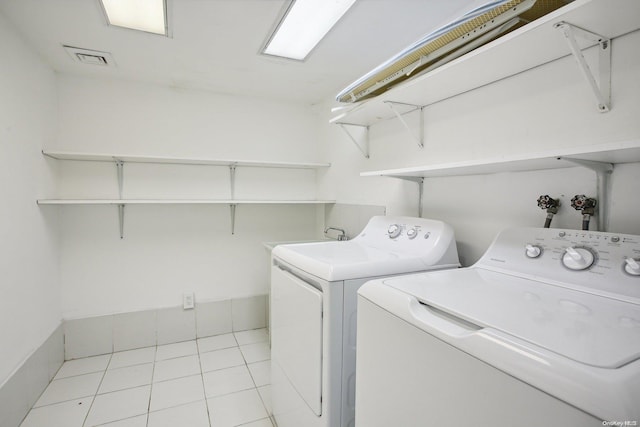 clothes washing area with light tile patterned floors and washing machine and clothes dryer