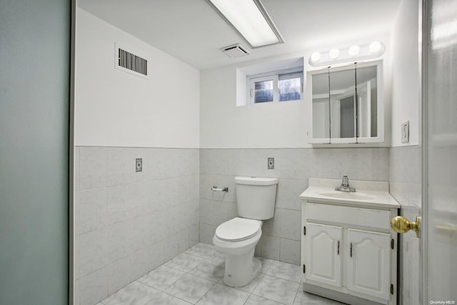 bathroom featuring vanity, toilet, and tile walls