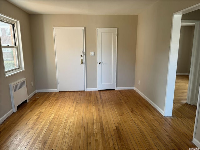 empty room with light hardwood / wood-style floors and radiator