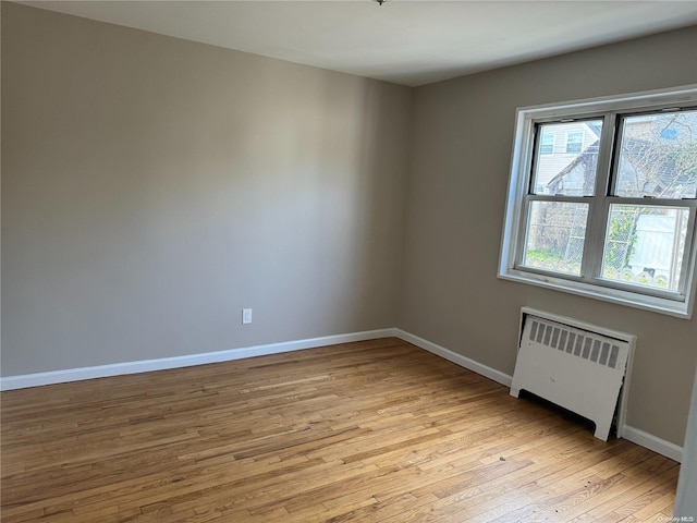 unfurnished room with radiator heating unit and light hardwood / wood-style flooring