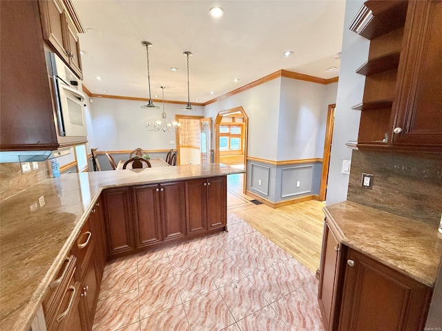 kitchen featuring a wainscoted wall, crown molding, open shelves, hanging light fixtures, and decorative backsplash