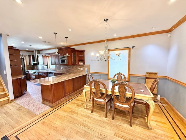 dining room with recessed lighting, light wood-style flooring, ornamental molding, wainscoting, and a chandelier