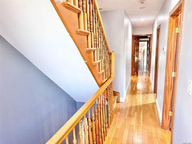 hallway featuring stairway, light wood-type flooring, and baseboards