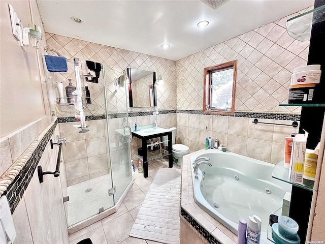 full bathroom featuring toilet, a tub with jets, a stall shower, and tile walls