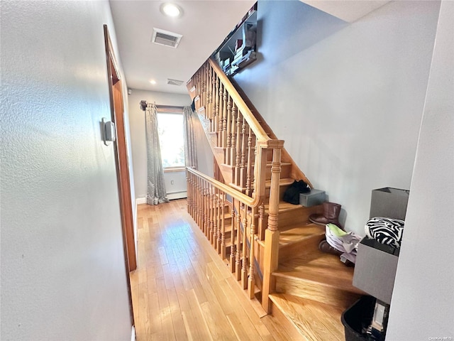 stairway featuring visible vents, baseboard heating, wood finished floors, and recessed lighting