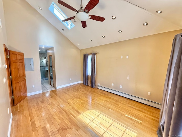 spare room with a skylight, a baseboard heating unit, high vaulted ceiling, light wood-type flooring, and electric panel