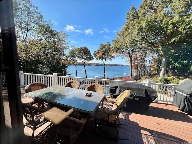 wooden deck with area for grilling, outdoor dining area, and a water view