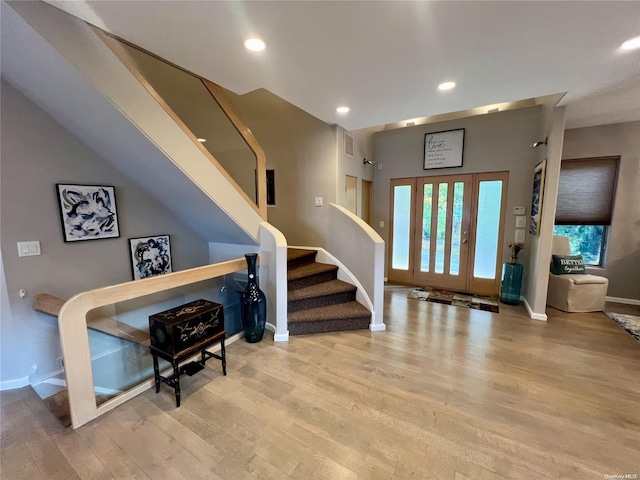 foyer with light wood-type flooring, baseboards, and stairway