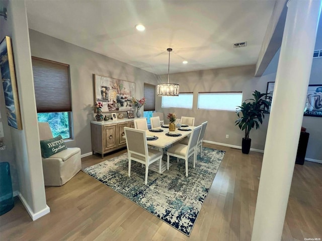 dining space featuring light wood-style floors, plenty of natural light, baseboards, and an inviting chandelier