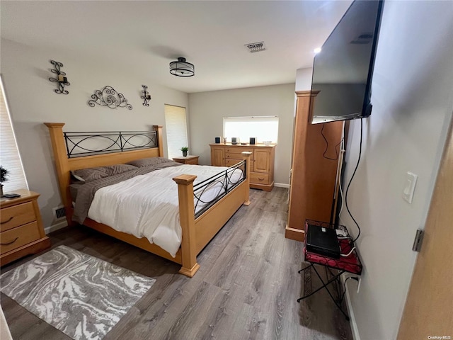 bedroom featuring light wood-style flooring, visible vents, and baseboards