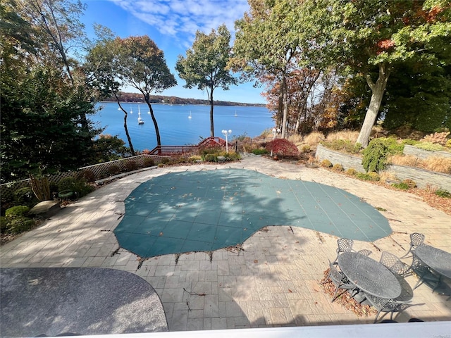 view of pool with a water view, a fenced in pool, and a patio