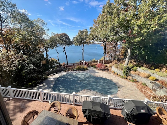 view of pool with grilling area and a deck with water view